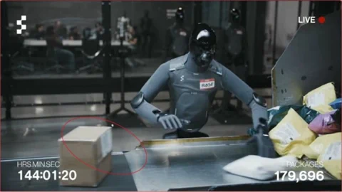 Figure F.03 robot makes a minor error, placing a package with the label facing up instead of down.